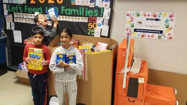 Clearbrook Elementary Food Drive 2023 Three students stand in front of large box filled with food donations