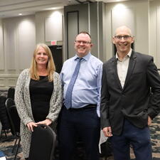 One Female and Two Males stand and smile for camera